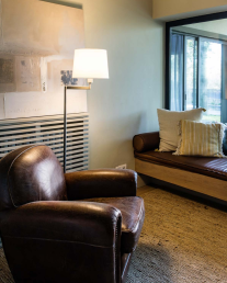 Klasická stojací lampa u čtecího koutku s koženým křeslem.