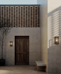 Vonkajšie nástenné svietidlá IL FANALE po stranách drevených dverí v kamennom dvore